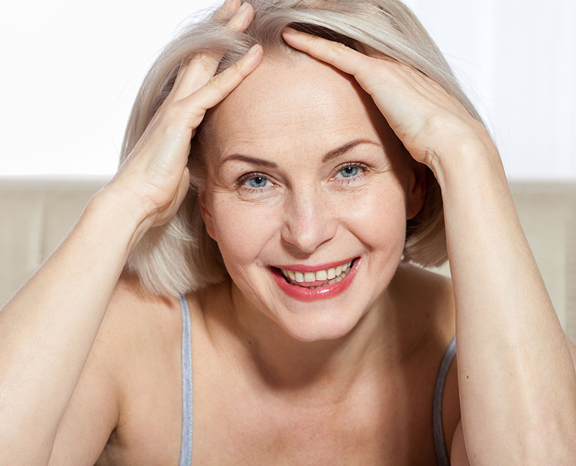 older woman looking at camera with hands in her hair