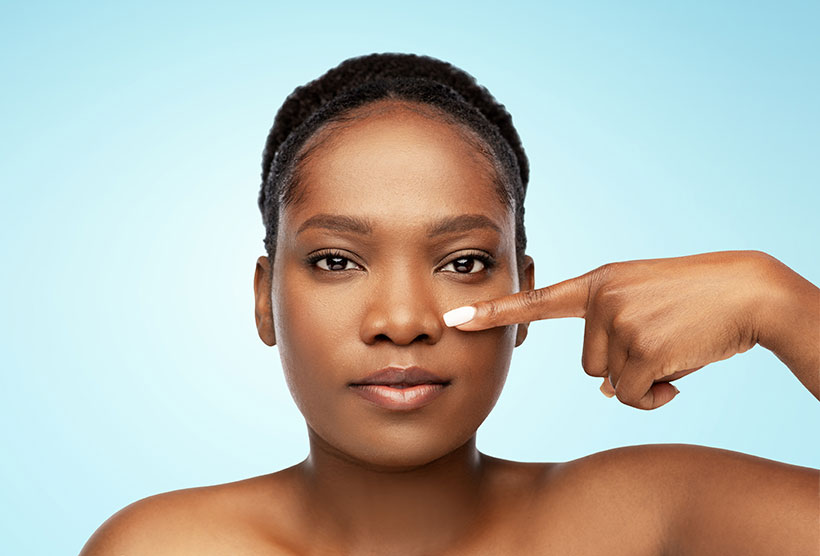 Woman looking at the camera and pointing to her nose