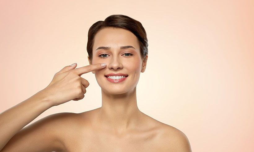 Smiling woman pointing to her nose and looking at the camera